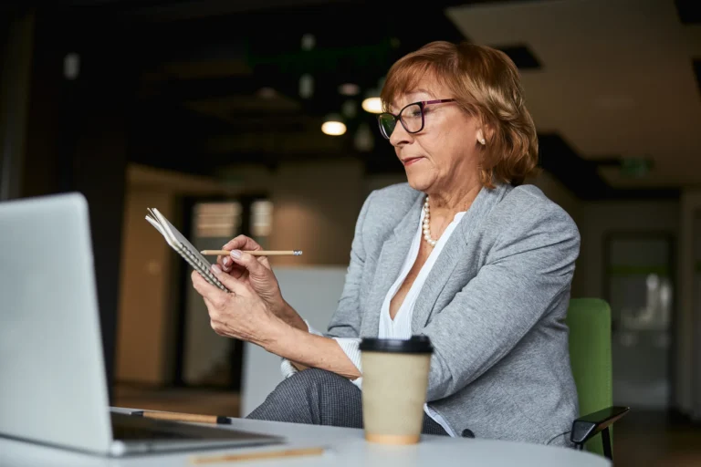 Woman taking notes beside her laptop